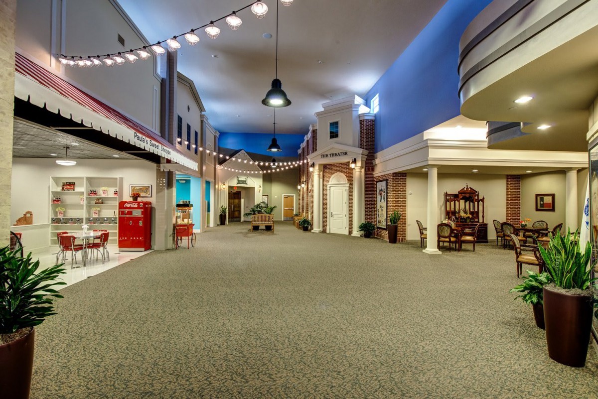 A spacious, well-lit indoor hallway features storefronts and decorative lighting.