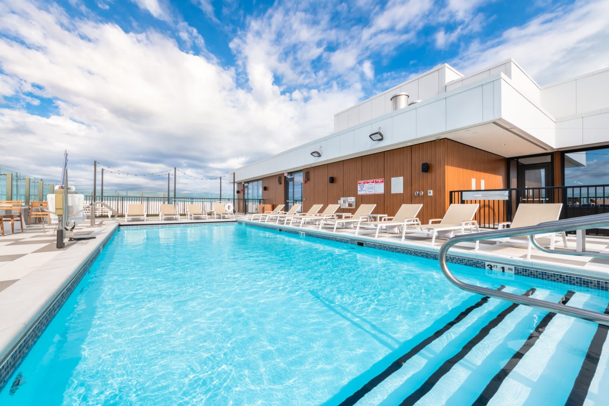 Rooftop swimming pool with lounge chairs on a sunny day.