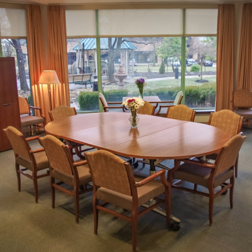 A spacious conference room featuring a large wooden table surrounded by chairs, illuminated by natural light from the windows.