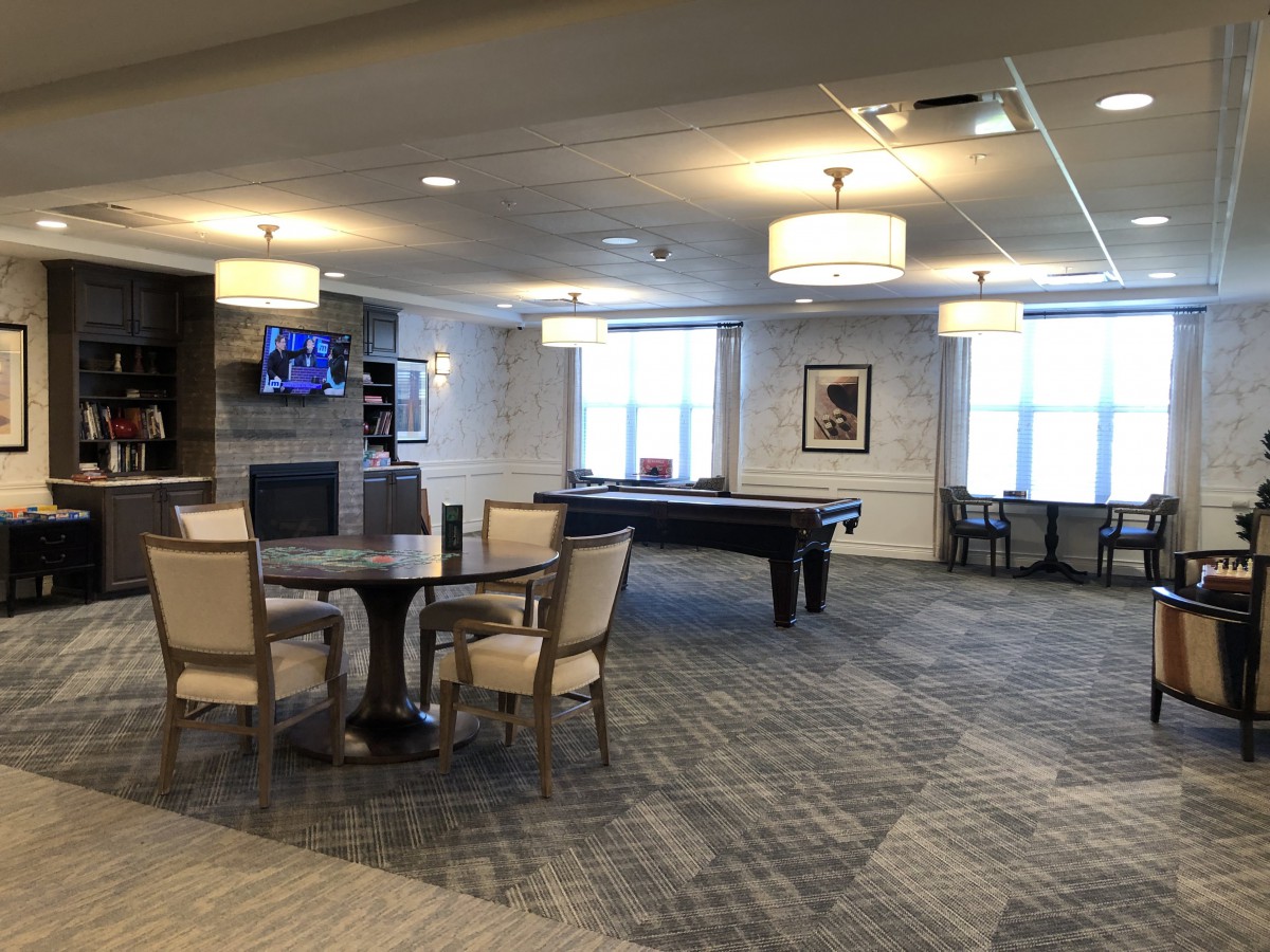 A modern lounge area featuring a pool table, seating arrangements, and a television.