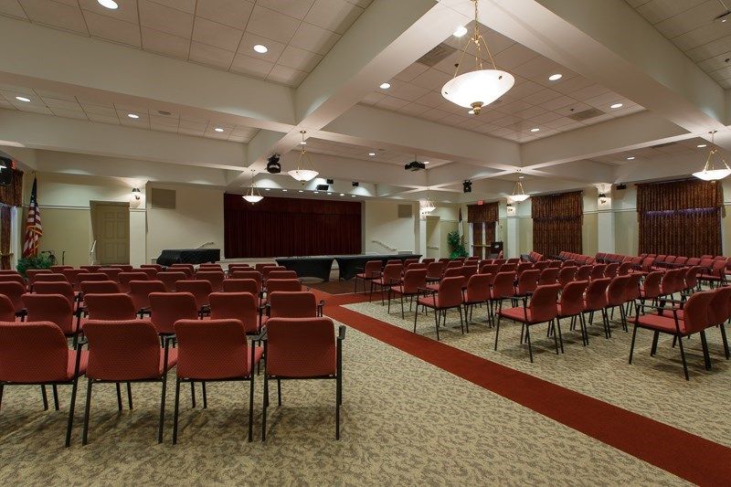 An empty conference room with rows of chairs facing a large projector screen.