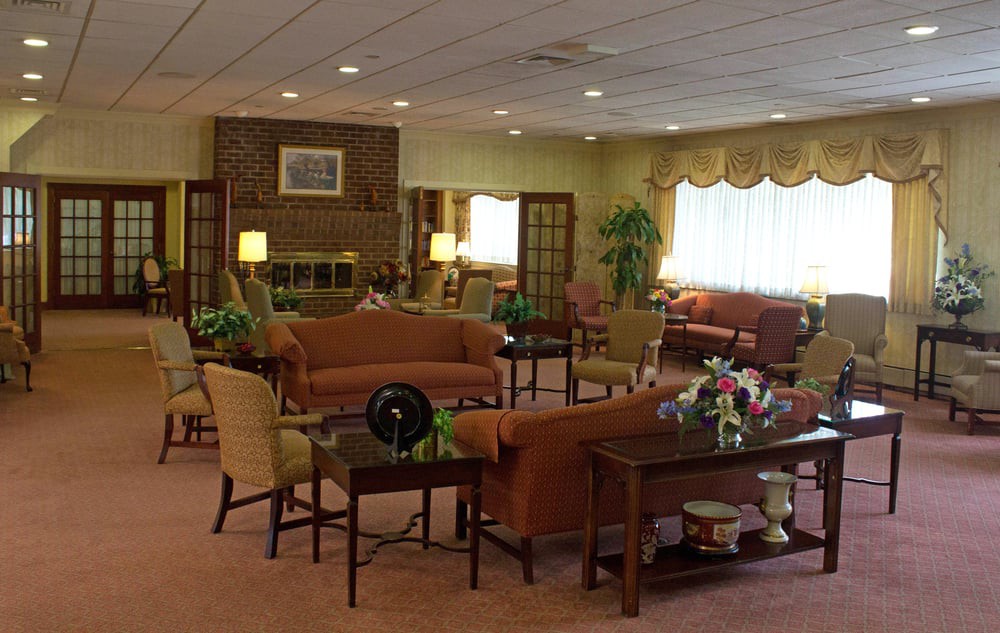 A cozy lounge area with sofas, chairs, and coffee tables, decorated with plants and lamps.