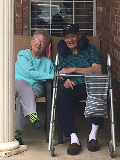 A cheerful elderly couple enjoying each other's company on their porch.