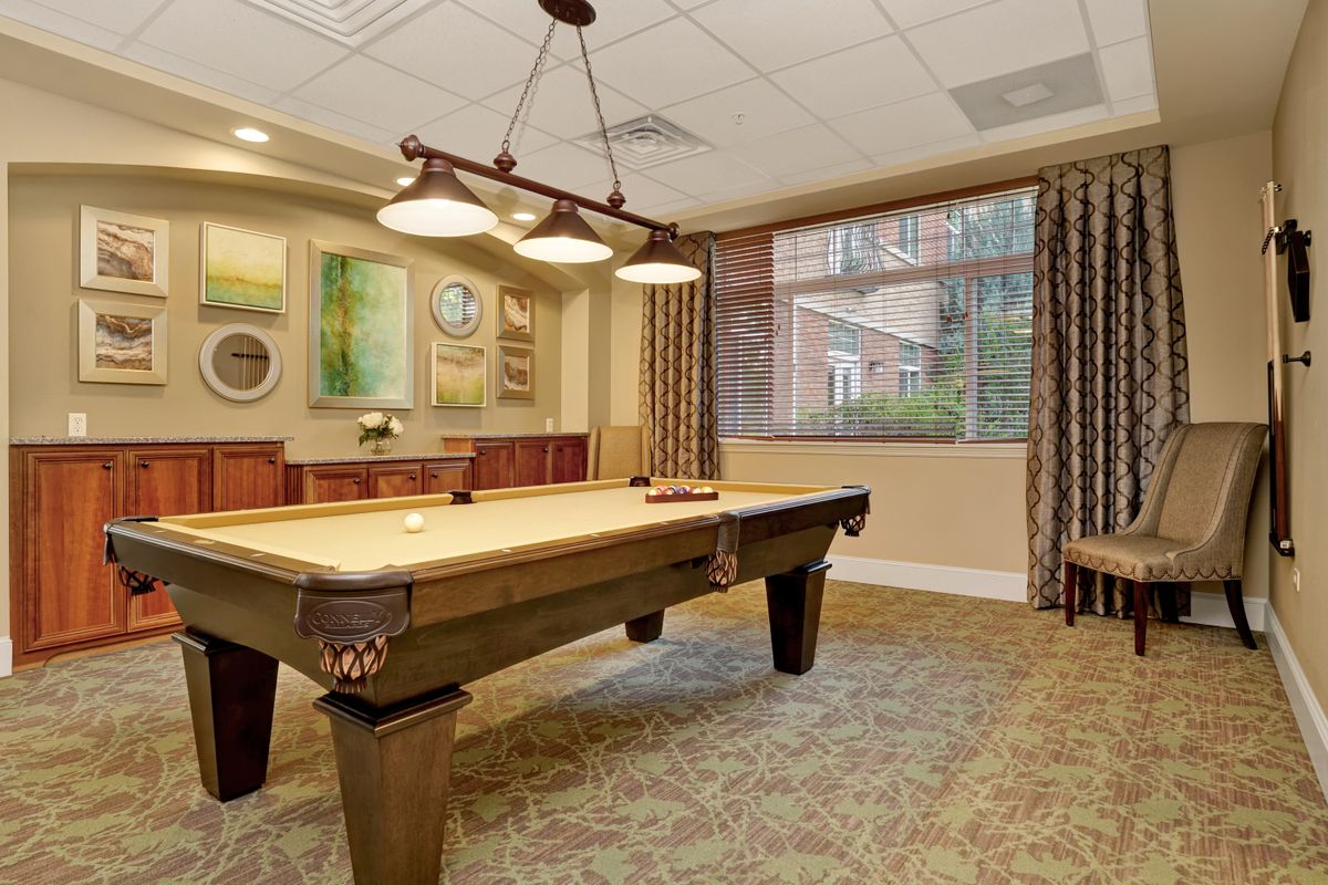 A cozy recreation room featuring a pool table, artistic decor, and warm lighting.