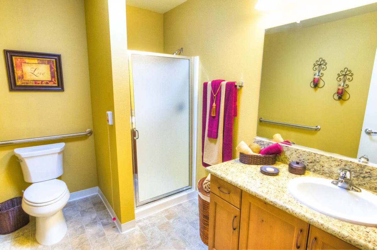 A well-lit bathroom featuring a shower, countertop sink, and colorful towels.