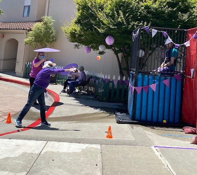 A person attempts to hit the target at a dunk tank during an outdoor event.