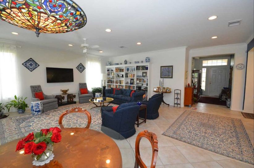 A cozy living room with a spacious seating area and a large TV, complemented by decorative bookshelves and a colorful stained glass light fixture.