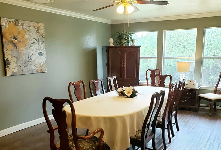 A formal dining room with a table set for gathering, featuring classic wooden chairs and a white tablecloth.
