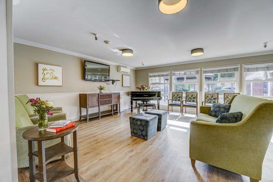A cozy and bright living room with a piano and comfortable seating.