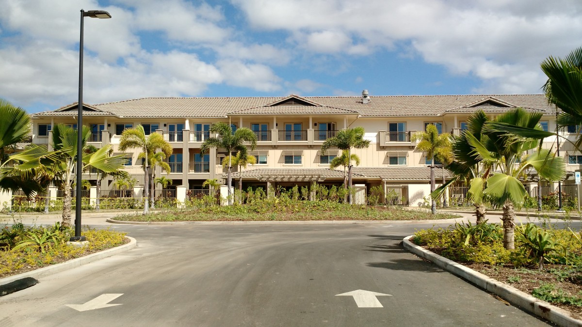 A modern building surrounded by palm trees under a partly cloudy sky.