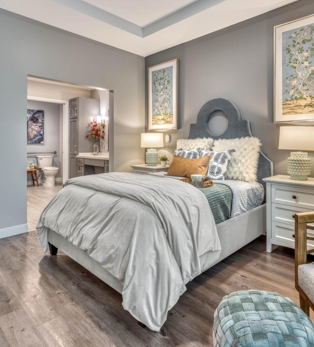 A modern and cozy bedroom with elegant decor, featuring a neatly made bed, matching nightstands, and stylish artwork.