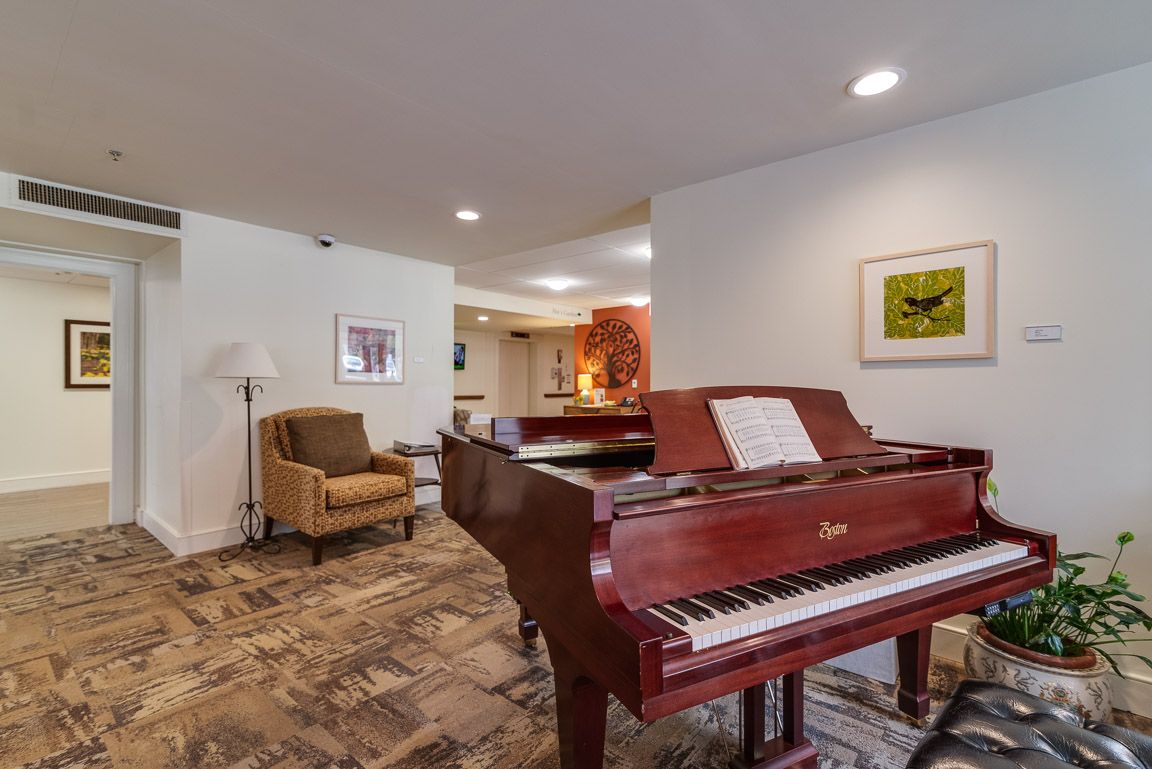 A cozy living room featuring a grand piano, comfortable armchair, and tasteful wall art.