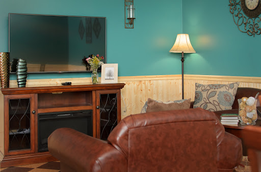 A cozy living room featuring a teal accent wall, modern television, elegant lamp, and comfortable seating.