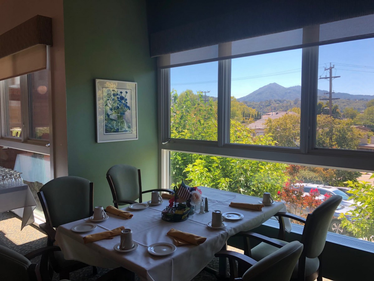A cozy dining area with a beautifully set table and a scenic view of the mountains through large windows.