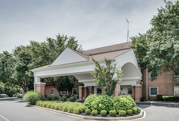 A view of a hotel entrance surrounded by lush greenery.