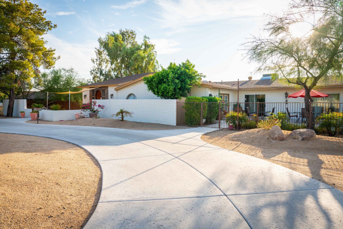 A suburban house with a wide driveway and neatly landscaped yard on a sunny day.