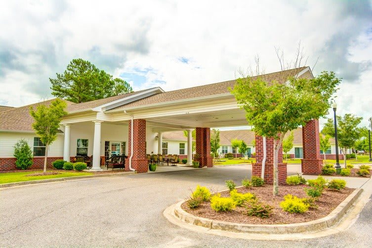 A welcoming building entrance with a covered driveway and manicured landscaping.
