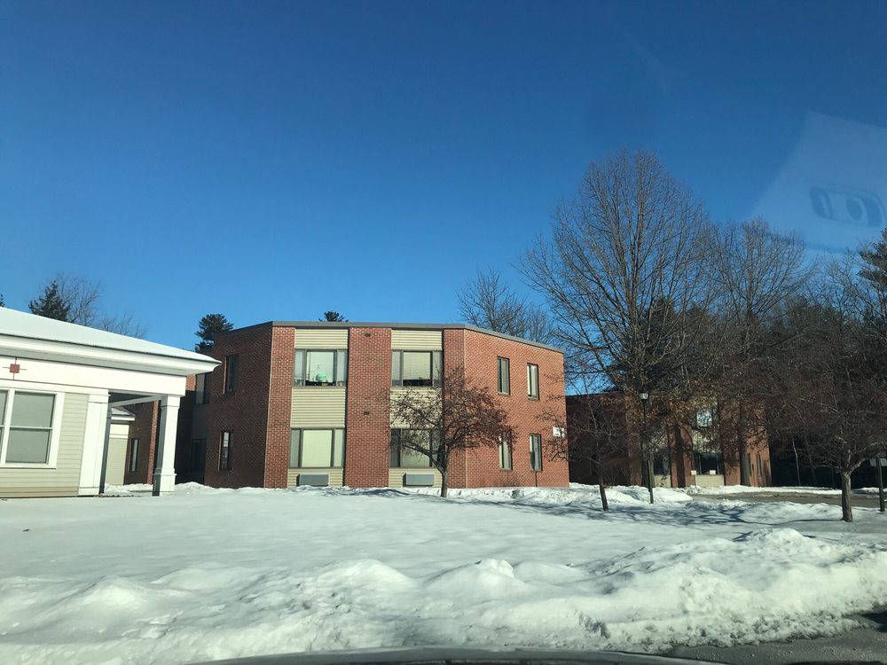 A brick residential building surrounded by snow under a clear blue sky.