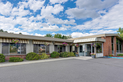 A welcoming entrance to a single-story building under a partly cloudy sky, surrounded by well-maintained landscaping.