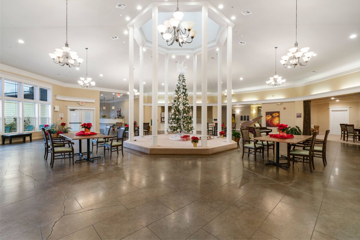 A spacious lobby adorned with a central Christmas tree, surrounded by festive decorations and elegant chandeliers.