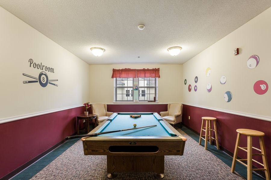A cozy game room with a pool table, featuring comfortable seating and wall decorations.