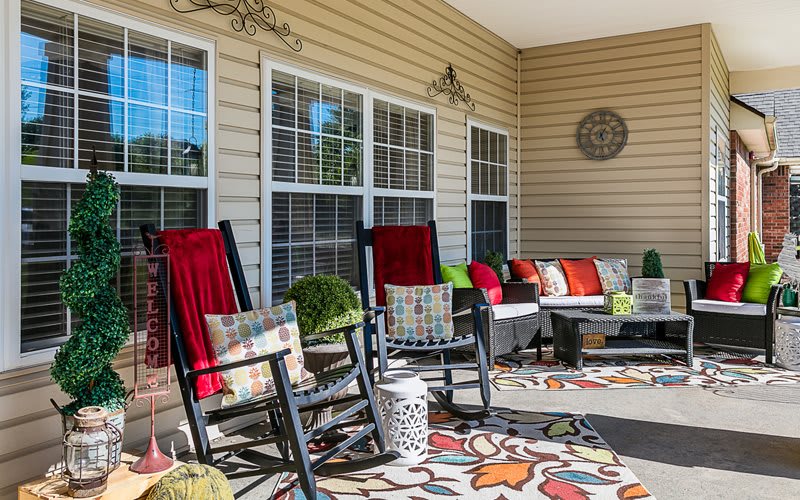 A cozy porch with rocking chairs, colorful cushions, and decorative elements.