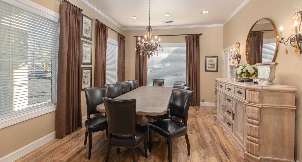 A stylish dining room with a long table, elegant chandelier, and wooden flooring.