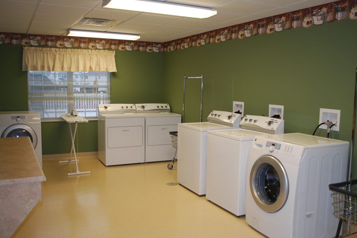 A laundry room featuring multiple washing machines and a dryer against green walls.