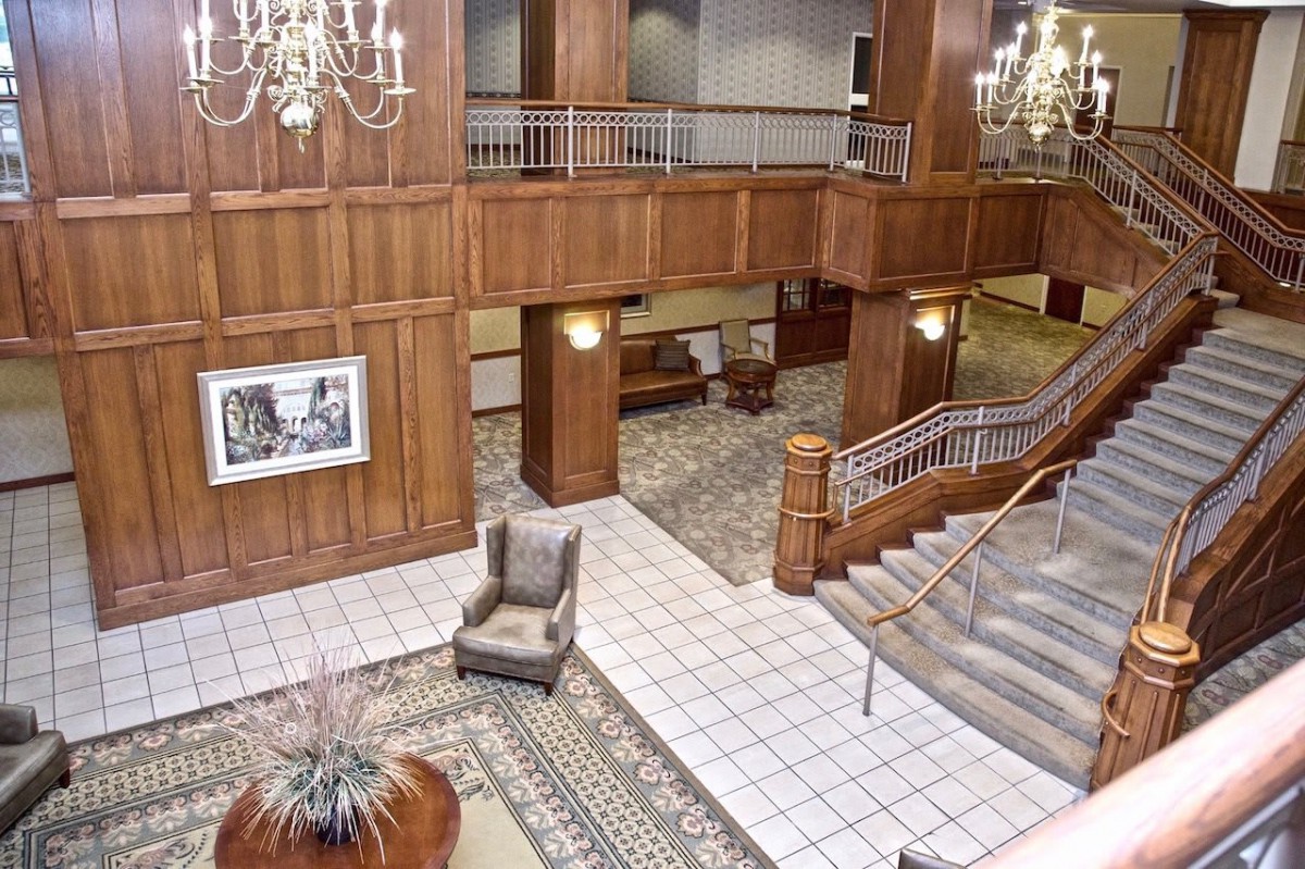 A luxurious hotel lobby featuring chandeliers, elegant staircases, and classic furniture.