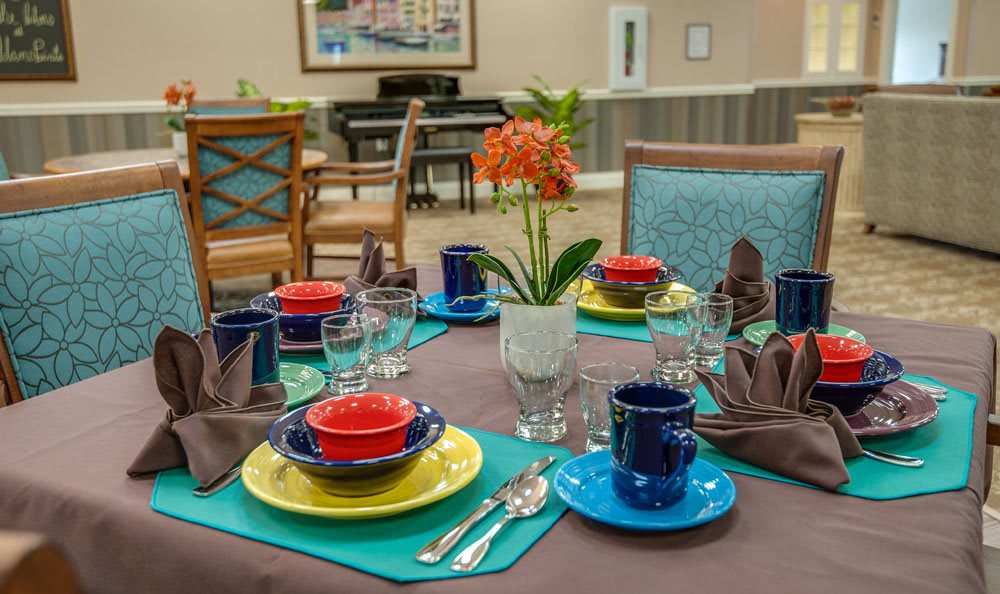 A dining table beautifully set with colorful dishes and a floral centerpiece.