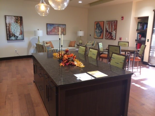 A modern dining room with a large table, surrounded by chairs and decorated with autumn-themed centerpieces.