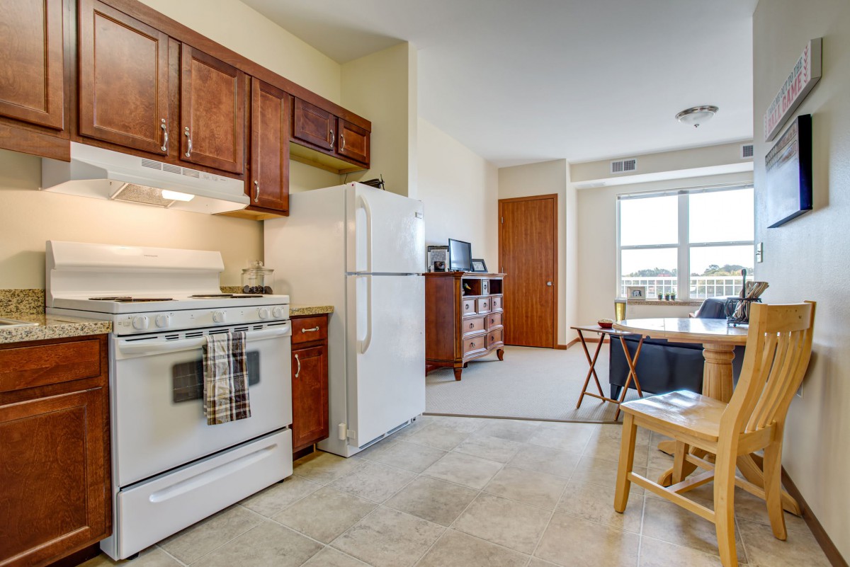A cozy apartment kitchen and dining area with wooden cabinets and a white refrigerator.