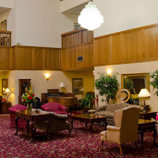 A spacious hotel lobby featuring elegant furniture, a large chandelier, and lush plants.