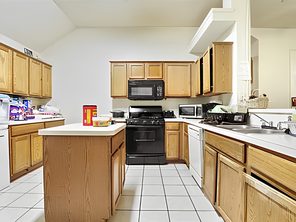 A modern kitchen with wooden cabinets, featuring an island and various appliances.