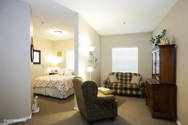 A cozy room featuring a bed and a small living area with an armchair and sofa.