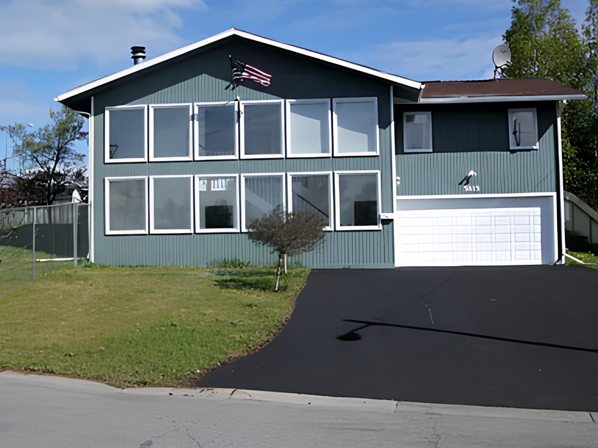 A residential house with large front windows, a garage, and a driveway.
