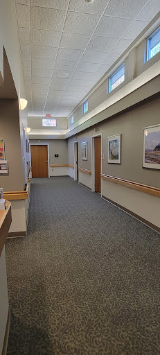 A well-lit hospital hallway featuring artwork and wooden doors.