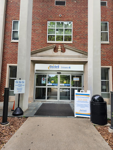 The entrance of a brick building featuring large glass doors and signage.