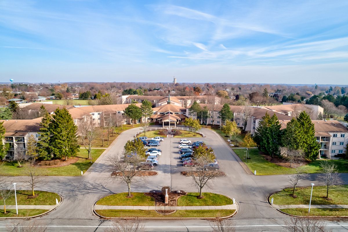 Aerial view of a large building with a parking lot surrounded by trees.