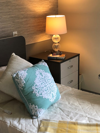 A cozy bedroom setup featuring a stylish lamp, decorative pillow, and modern nightstand.