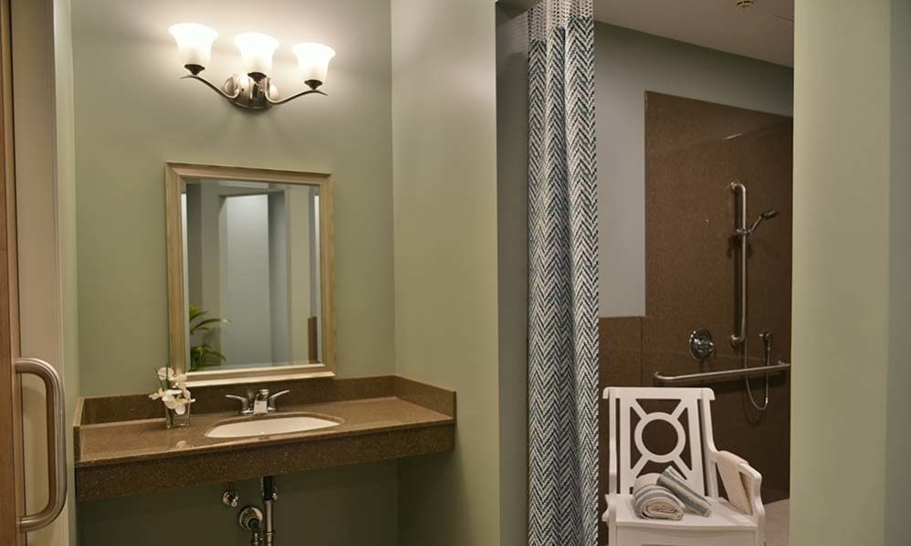 A modern bathroom with a wall-mounted sink, mirror, and decorative lighting fixture.