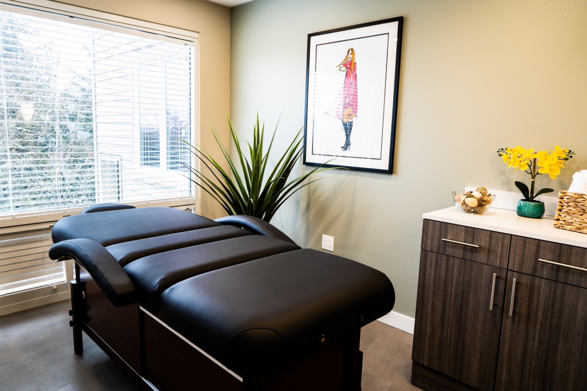 A serene therapy room with a massage table, modern decor, and natural light.