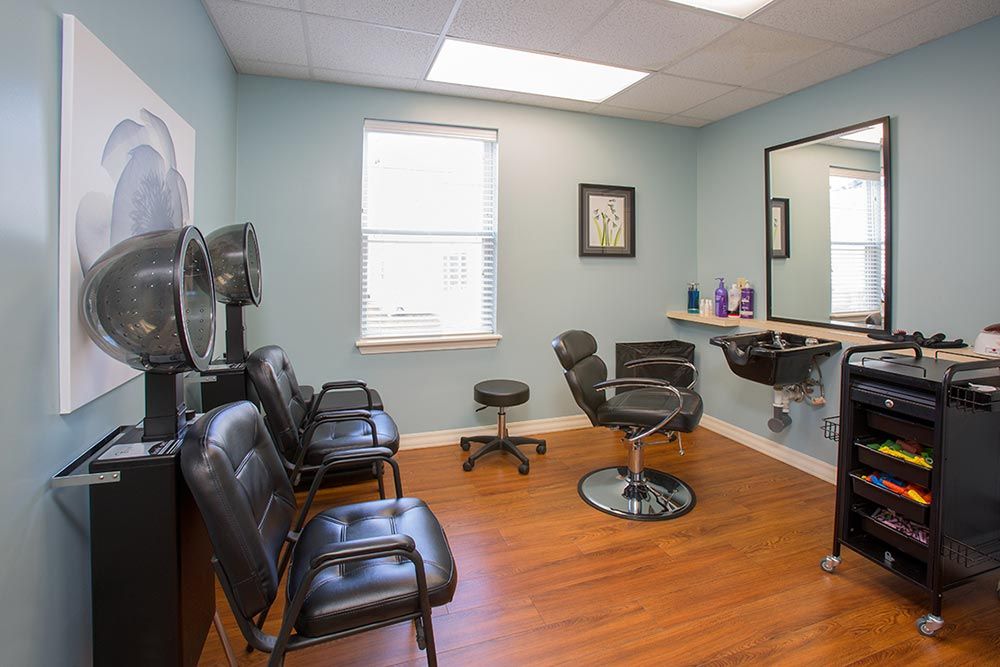 A cozy salon interior with chairs, mirror, and hair styling equipment.
