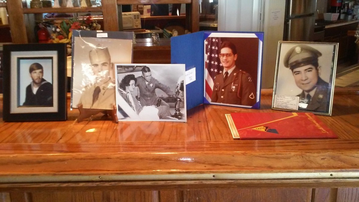 A collection of vintage military photographs and memorabilia displayed on a wooden surface.