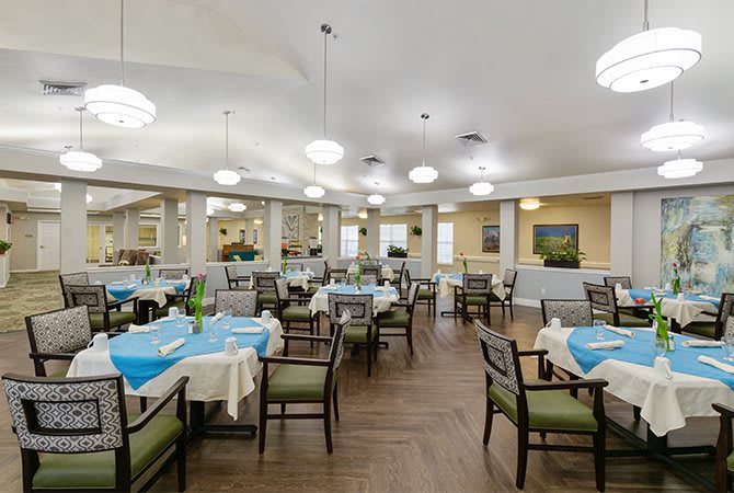 A well-lit dining room with neatly arranged tables and chairs.