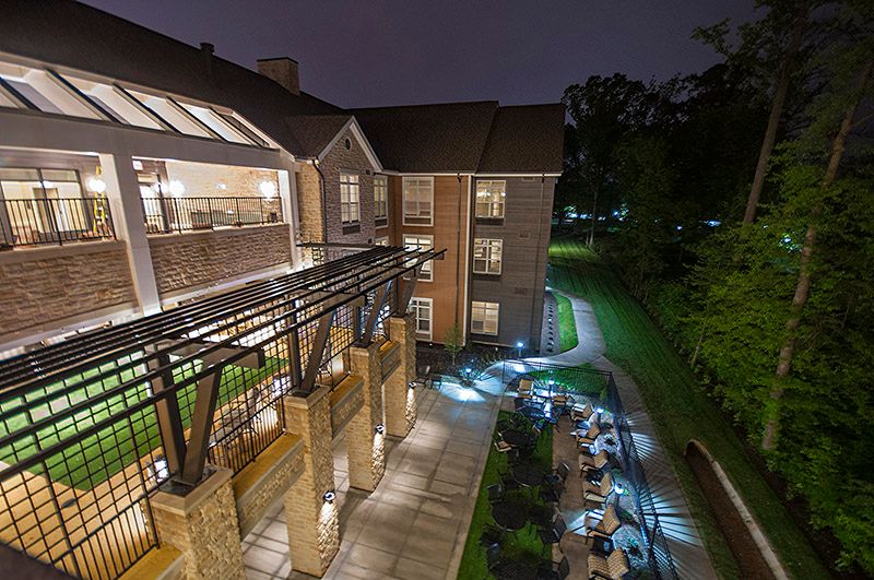 A well-lit building at night, with a pathway and surrounding greenery.