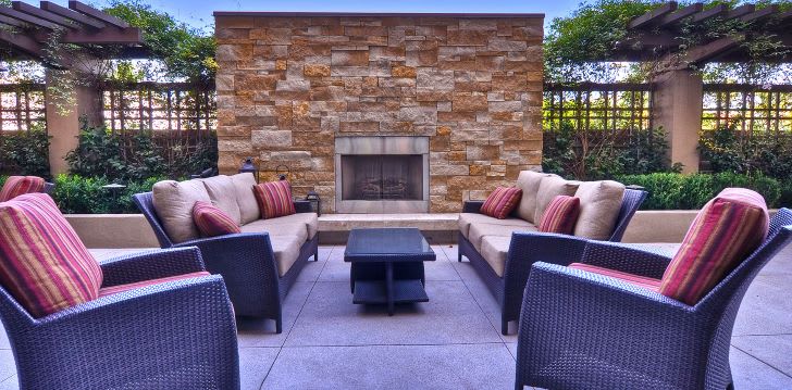 A cozy outdoor patio with comfortable seating and a stone fireplace.
