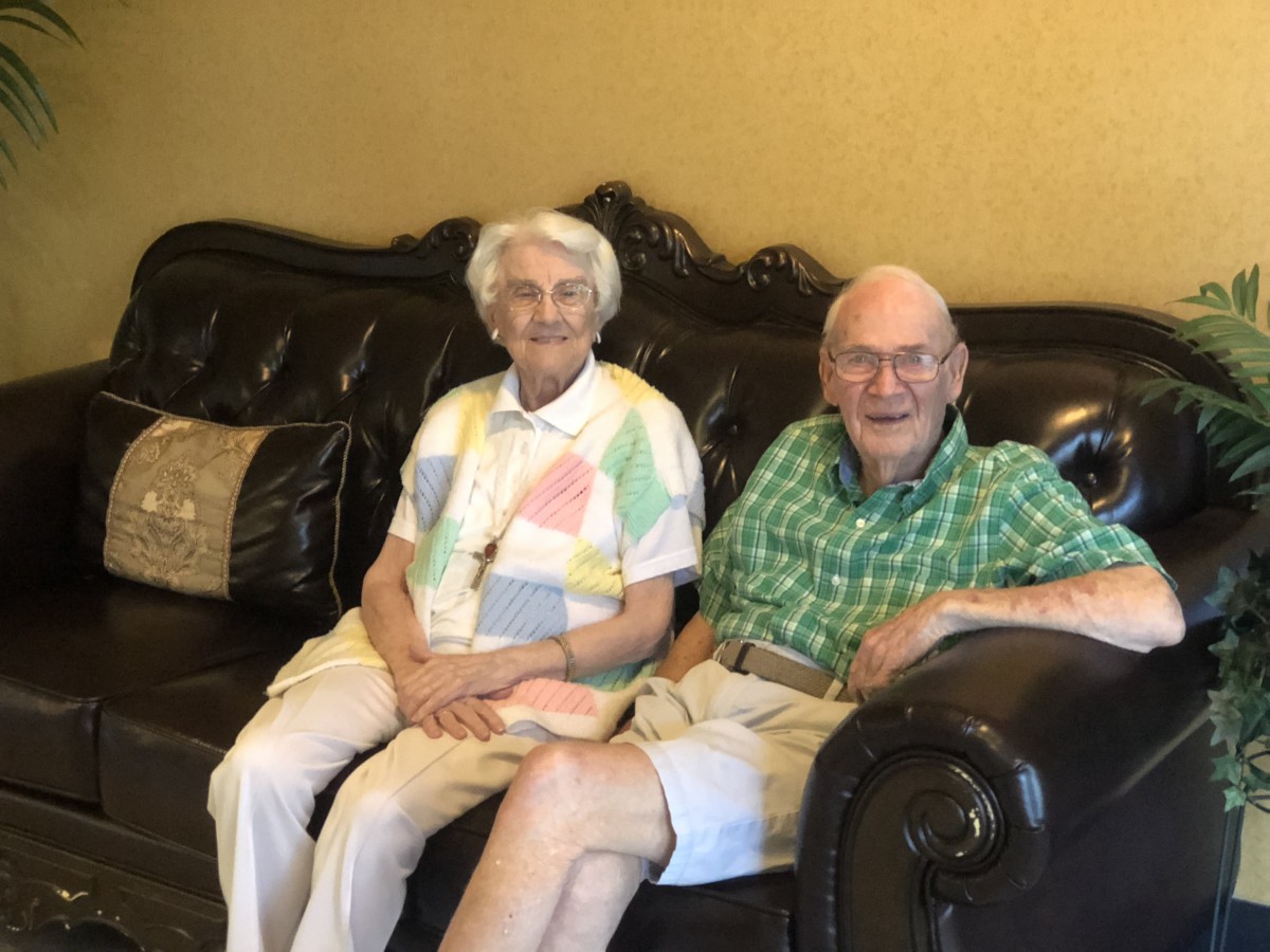 An elderly couple sitting together on a sofa in a living room.
