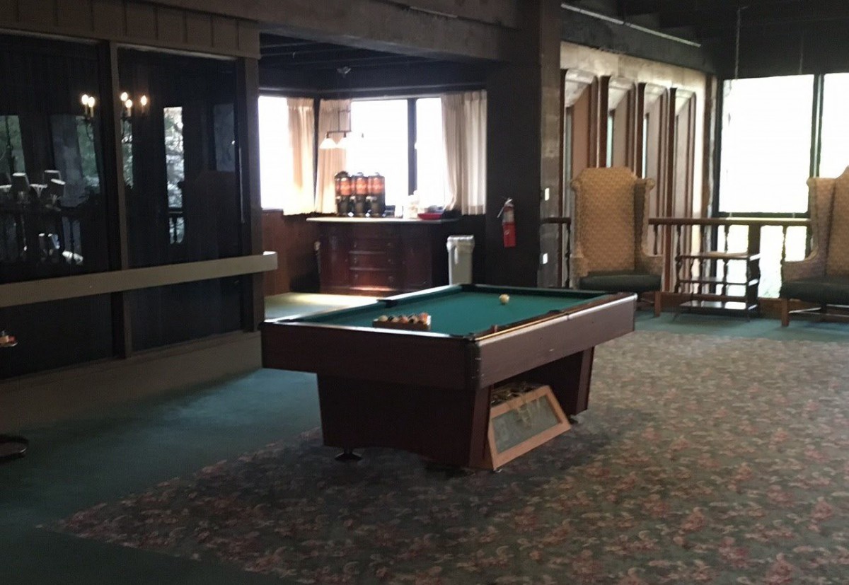 A dimly lit game room featuring a pool table with billiard balls set up.