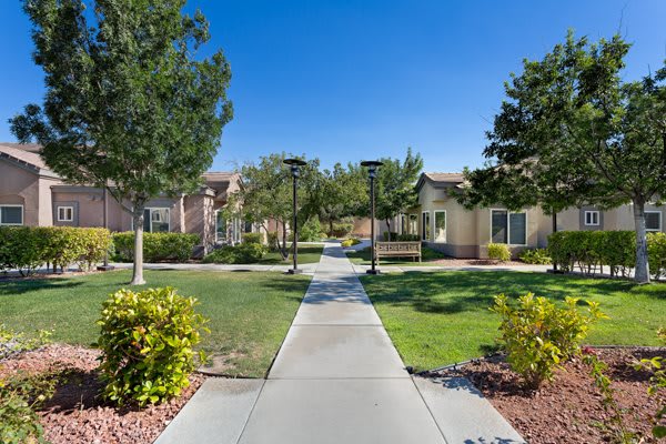A well-maintained residential area with a central walkway surrounded by greenery and trees.